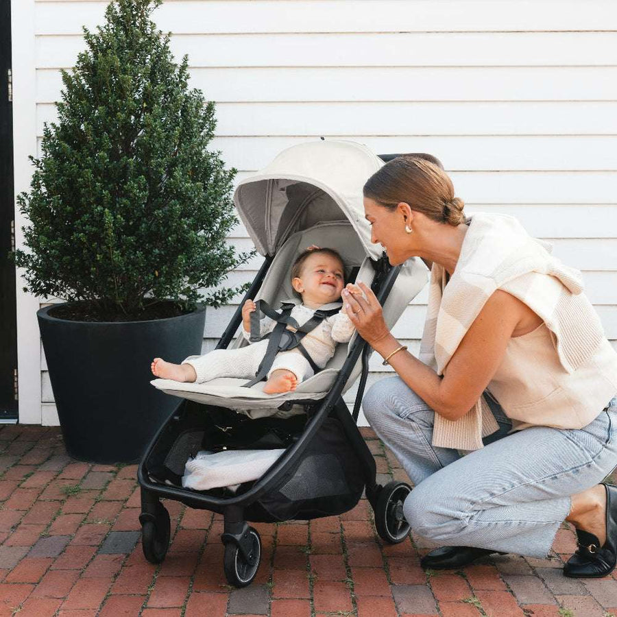 UPPAbaby Minu V3 stroller in beige fabric with caregiver and baby outdoors