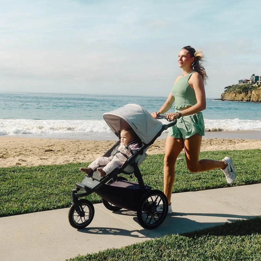 UPPAbaby Ridge V2 Stroller pushed along a seaside path by an active parent