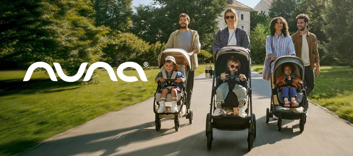 Nuna stroller collection with three families pushing children along a sunny park path