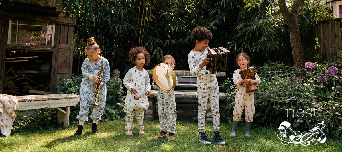 Nest Designs Fall/Winter 2026 kids sleepwear collection with five children playing musical instruments outdoors