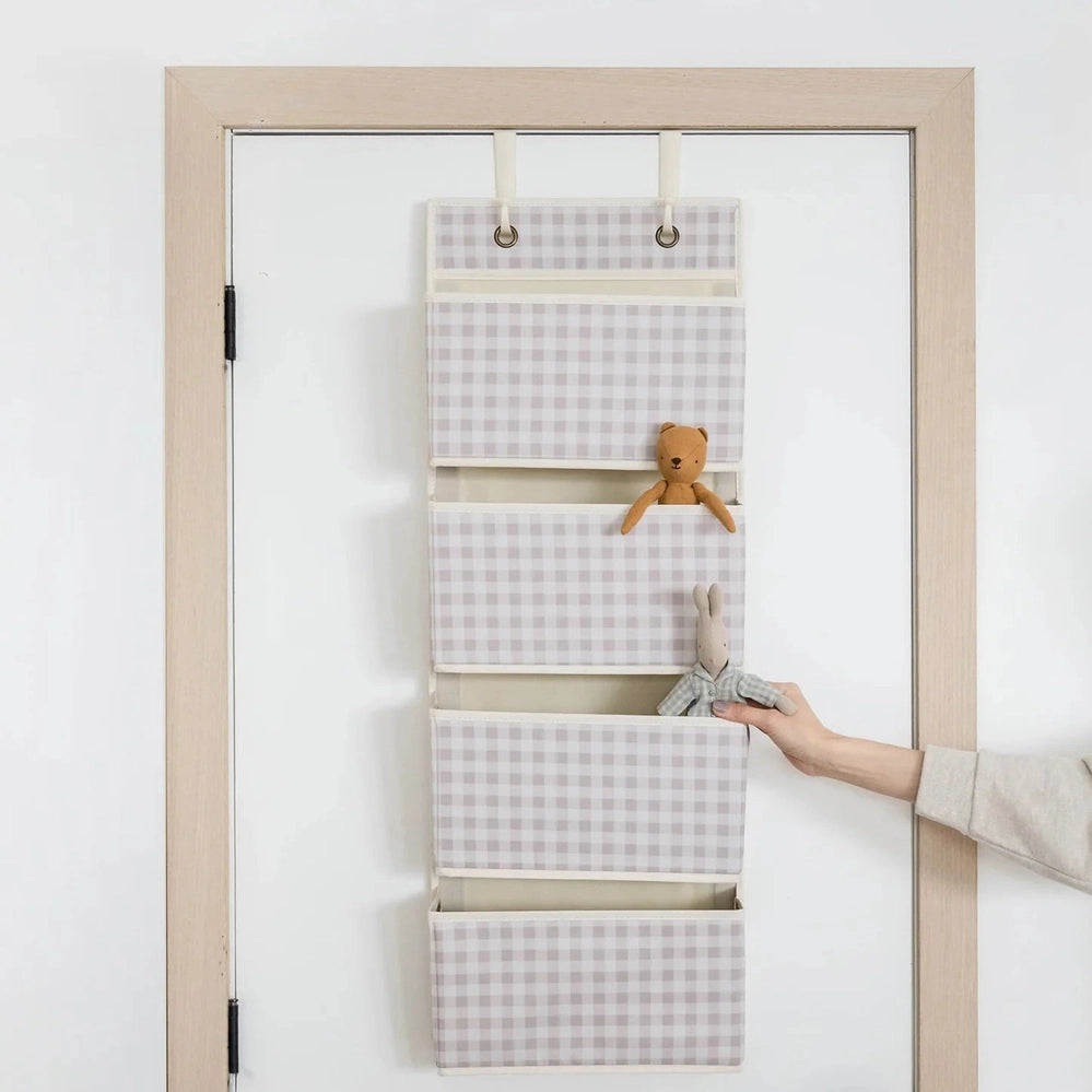 3 Sprouts gingham beige fabric over-the-door organizer with five pockets on a door; teddy and bunny toys shown