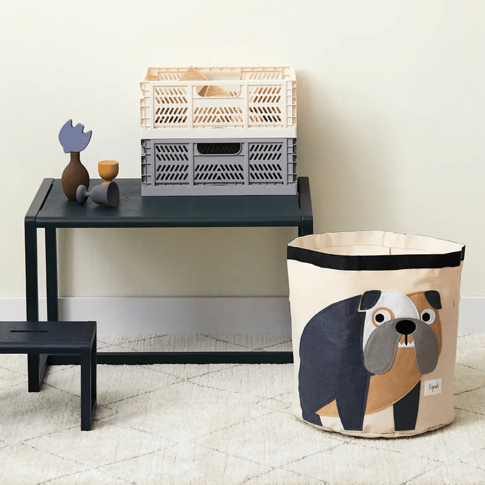 3 Sprouts Storage Bin in beige dog-print tote resting on a dark table beside stacked plastic crates.