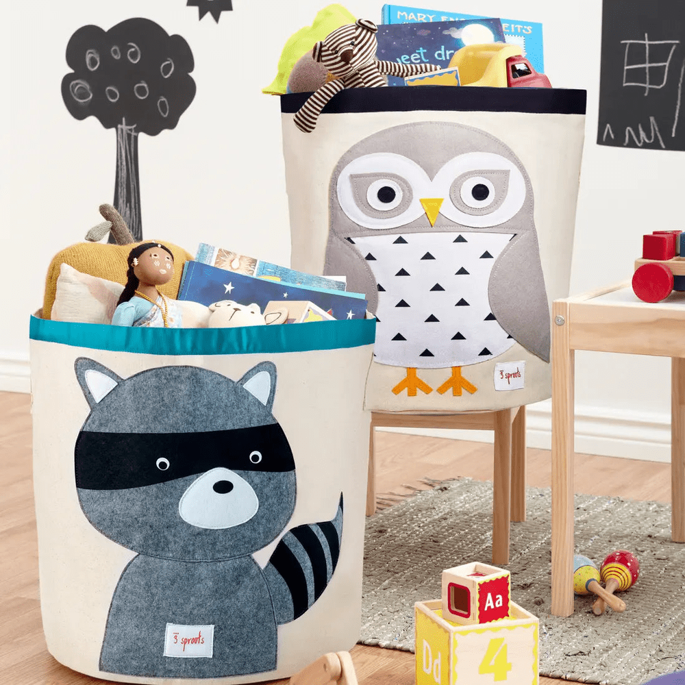 3 Sprouts Storage Bin duo with owl and raccoon designs, filled with toys in a kids' playroom.