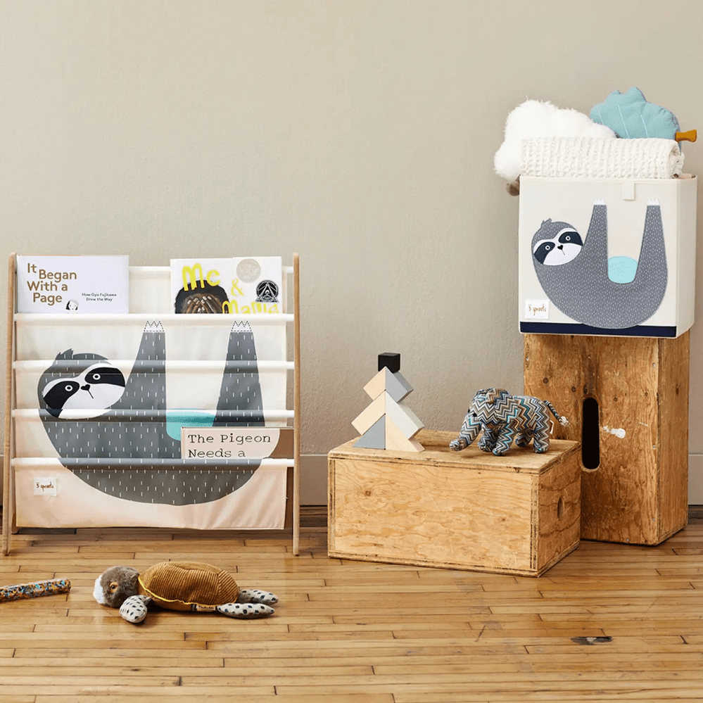 3 Sprouts Storage Box with blue sloth graphic perched on a wooden crate, keeping the nursery organized.