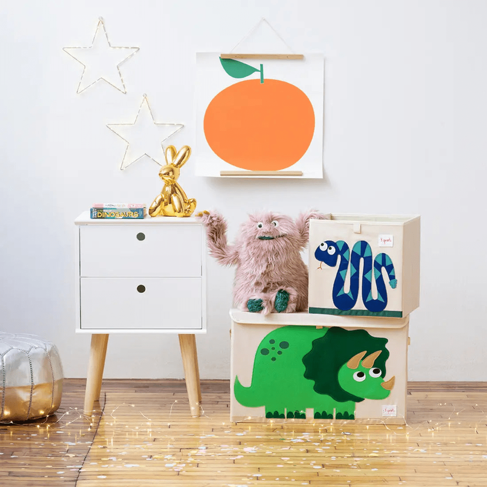 3 Sprouts Toy Chest in white with dinosaur artwork bins stacked beside a white dresser in a cozy kids’ room.