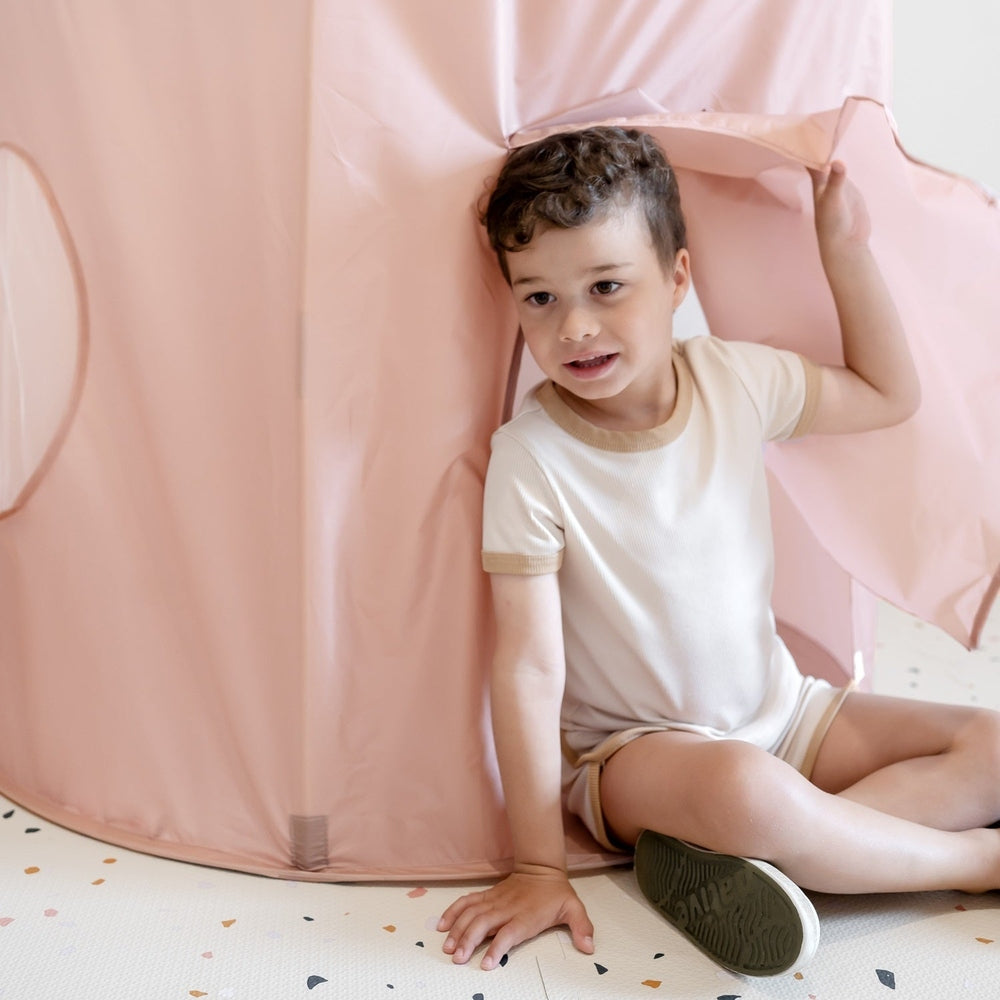 3 Sprouts Recycled Fabric Play Tent Castle in pink; a child sits inside, holding the doorway flap.