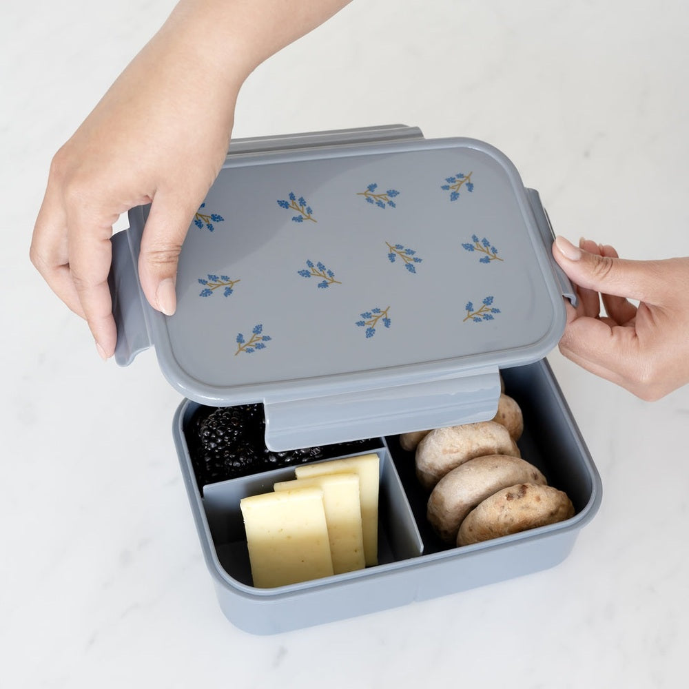 3 Sprouts recycled plastic bento box in gray with blue floral lid, open to show cheese, blackberries, and potatoes.