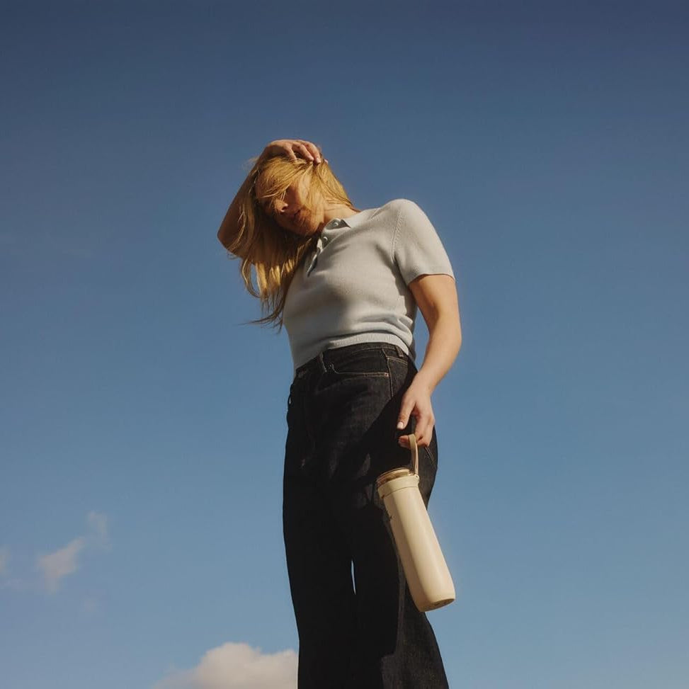 Person holding a cylindrical object against a clear blue sky