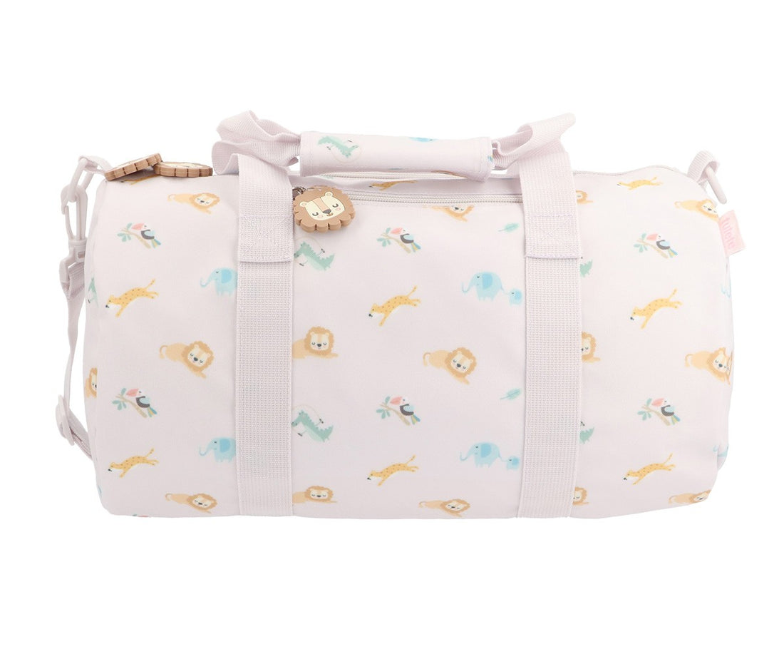 A cylindrical duffel bag in a very pale pink or off-white fabric, covered in a playful pattern of small cartoon animals including lions, giraffes, elephants, and butterflies in soft pastel colors. It features two top handles, a detachable shoulder strap, and a small decorative lion charm.