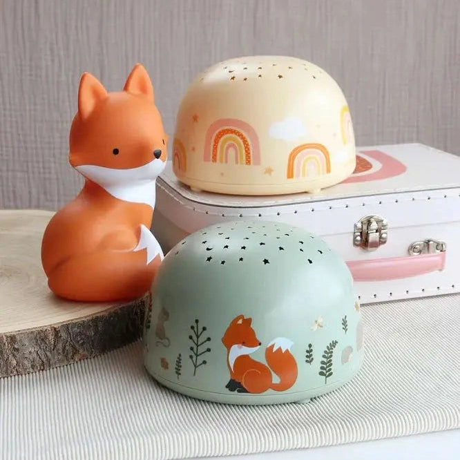 A Little Lovely Company Projector Night Light set: mint green dome with fox and star cutouts beside an orange fox figurine.