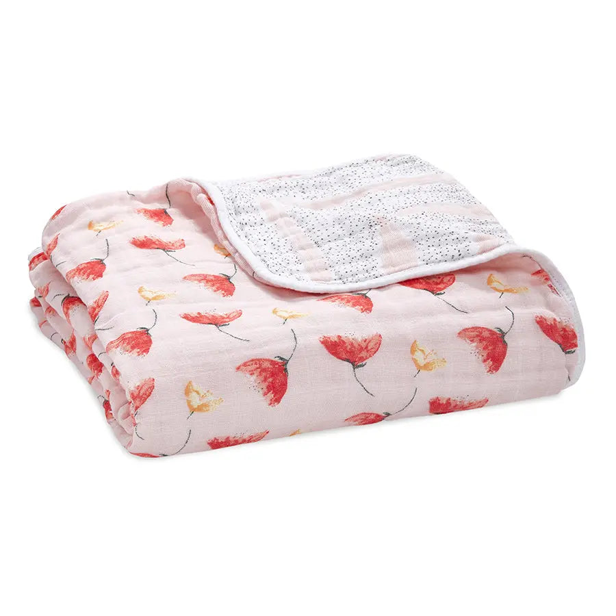 Aden+Anais Classic Dream Blanket folded on a surface, pale pink with red floral print and soft muslin texture.