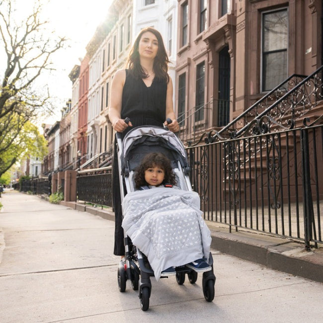 Aden+Anais Embrace Cross-Hatch Weighted On-The-Go Blanket on a stroller with a baby, gray pattern.
