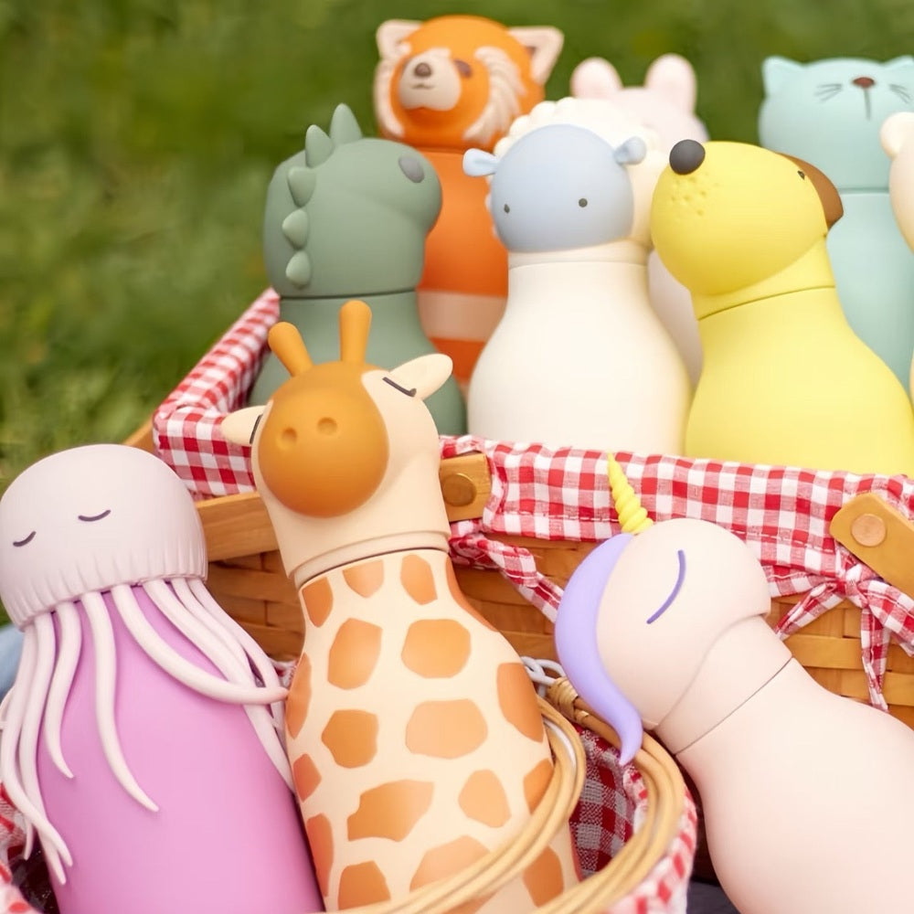 Colorful animal-themed water bottles in a basket with a grassy background