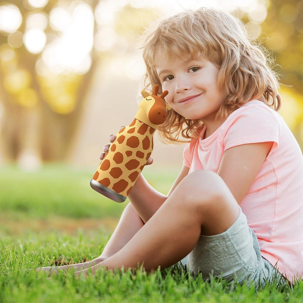 Asobu Bestie Animal 16oz double-wall stainless bottle with giraffe print, held by a smiling child outdoors.