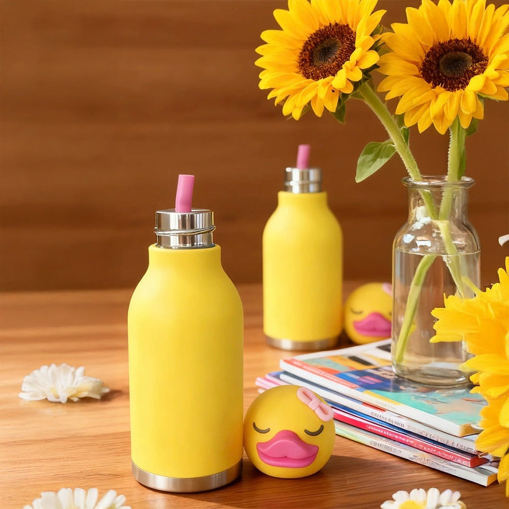 ASOBU Bestie Animal 16oz yellow double-wall stainless steel bottle with pink straw, shown with ducky toy and sunflowers.