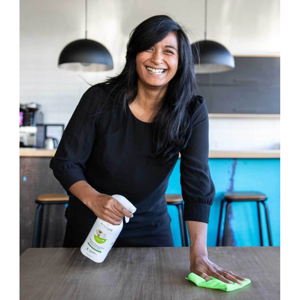 Attitude multi-surface disinfectant 800 ml bottle being used by a woman wiping a table with a lime green cloth