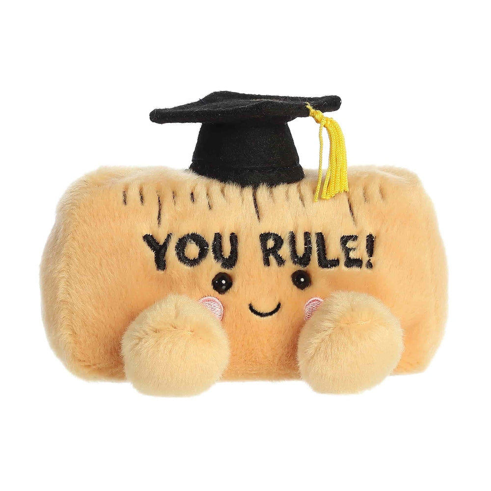 Aurora Palm Pals You Rule Ruler 5-inch plush toy in peach-beige with a black graduation cap and yellow tassel