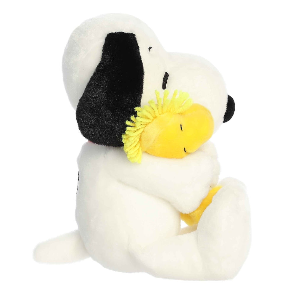 Aurora Snoopy and Woodstock 12-inch plush stuffed animals; white Snoopy with black ears hugging yellow Woodstock.