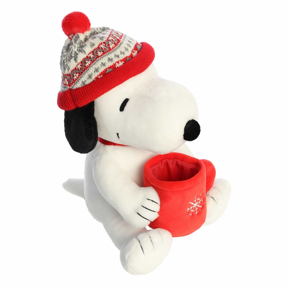 Aurora Snoopy stuffed animal wearing a red knit winter hat, holding a red mug with a snowflake design