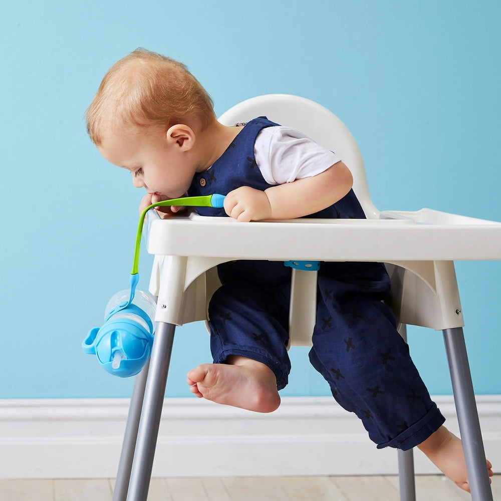 B.Box Connect A Cup sippy cup in blue attached to a high chair tray as baby drinks from the straw.