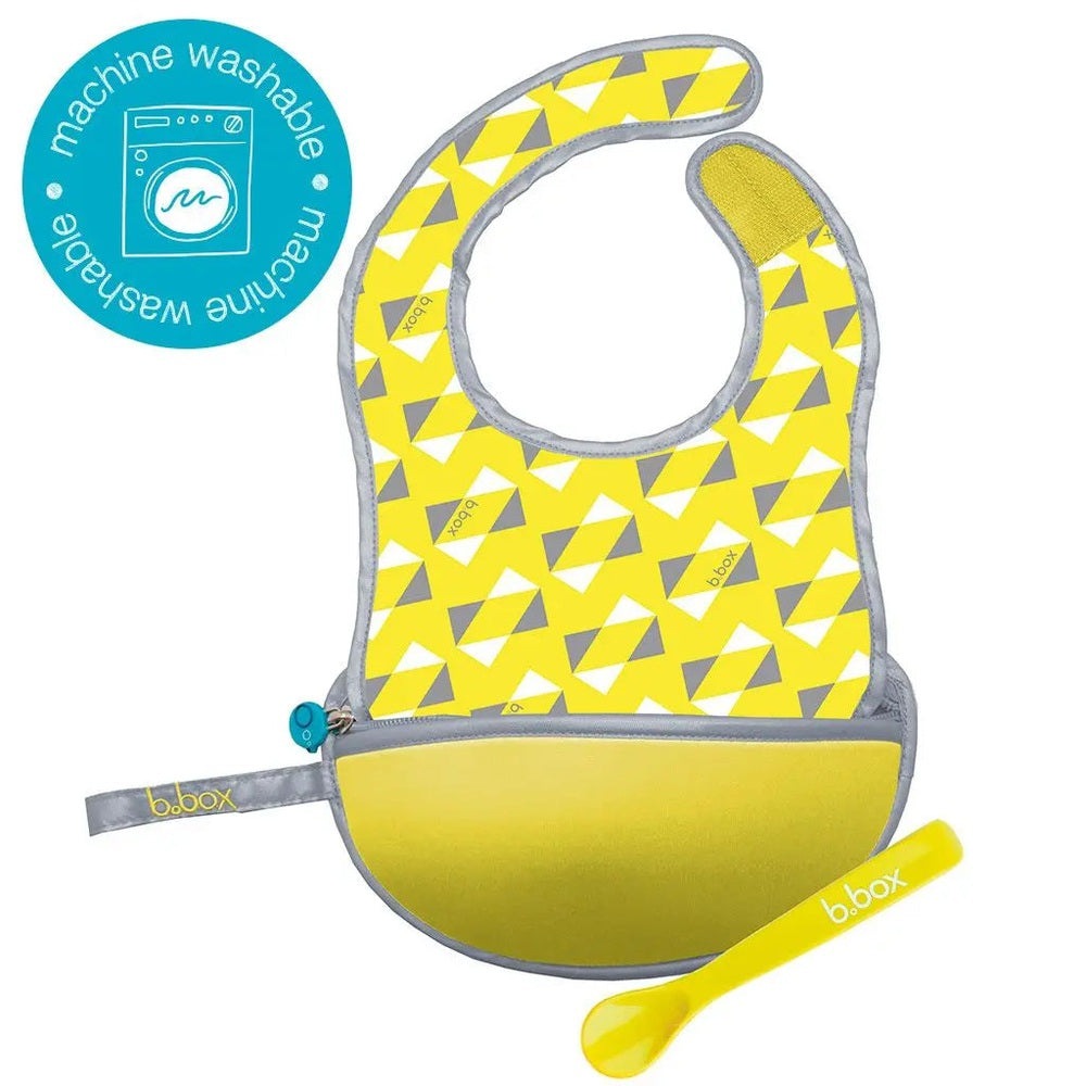 B.Box Travel Bib in bright yellow geometric print with grey trim and pocket; includes matching yellow spoon.