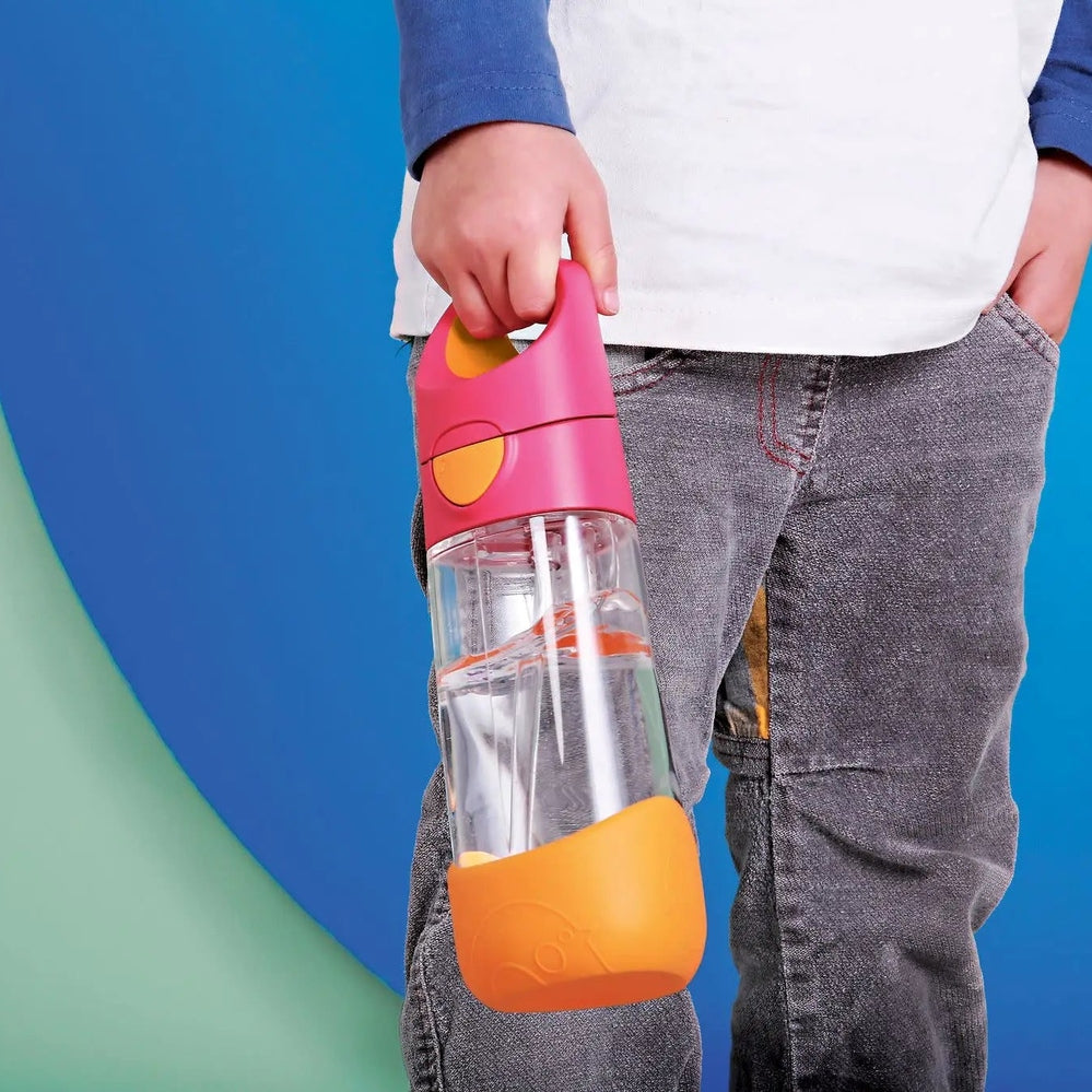B.Box Tritan Drink Bottle for kids; child holds pink-lidded bottle with orange grip and clear body.