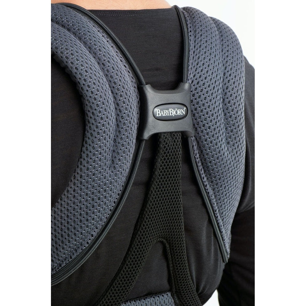 BabyBjörn Baby Carrier Free in dark gray mesh worn on back, showing padded straps and center logo buckle.