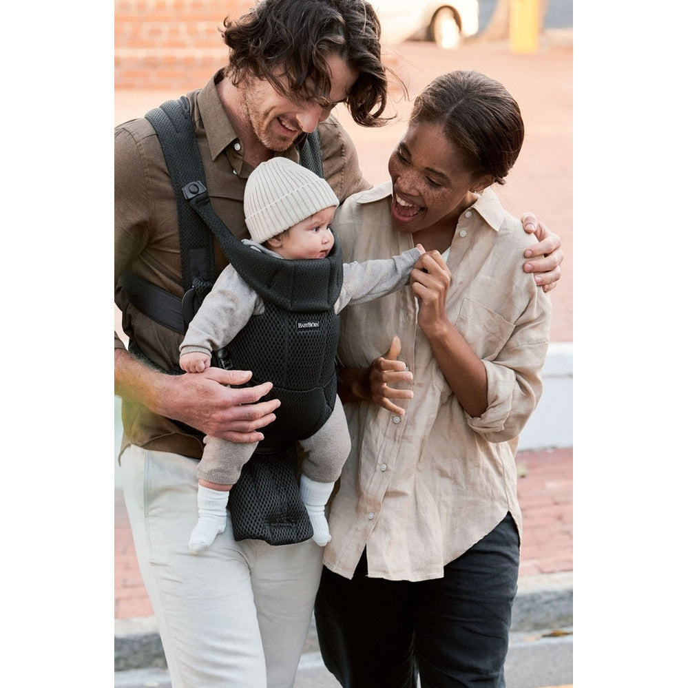 BabyBjörn Baby Carrier Free in black mesh worn by parents as they carry and play with baby in front carrier.