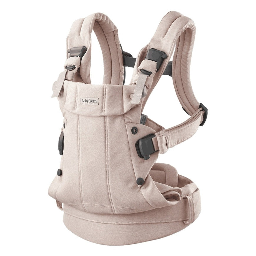 BabyBjörn Harmony baby carrier in beige, padded straps buckled, worn on a parent's torso.