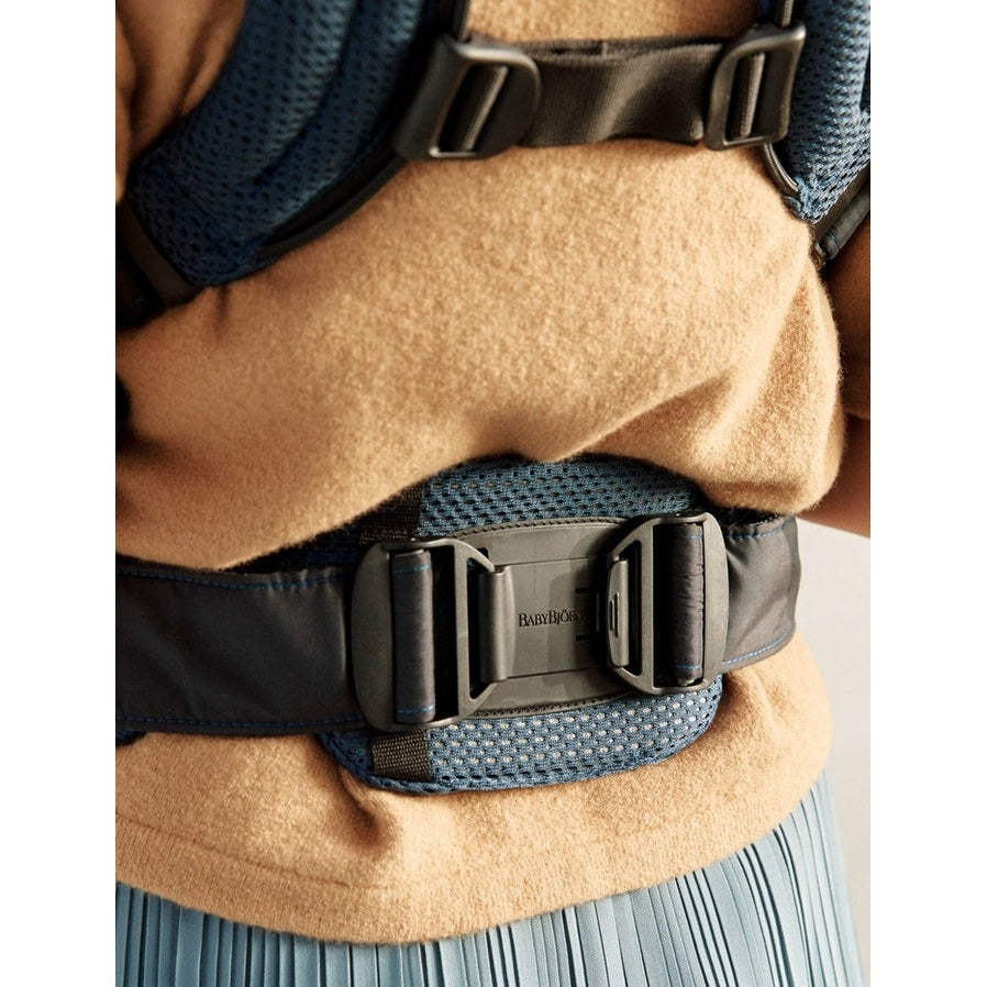 BabyBjörn Baby Carrier Harmony worn around the waist with secure side-release buckles and navy mesh straps.