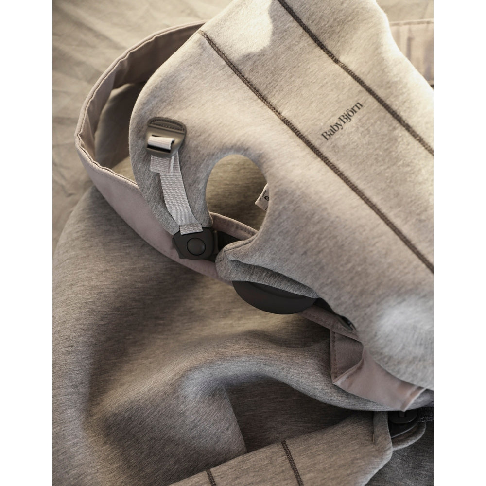 BabyBjörn Baby Carrier Mini in gray fabric, showing adjustable strap with buckle for secure, ergonomic fit.