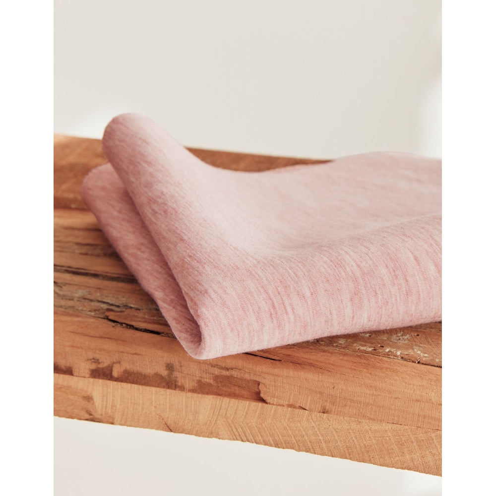 BabyBjörn Bouncer Bliss pink fabric folded on a wooden table, showcasing soft textile and compact setup.