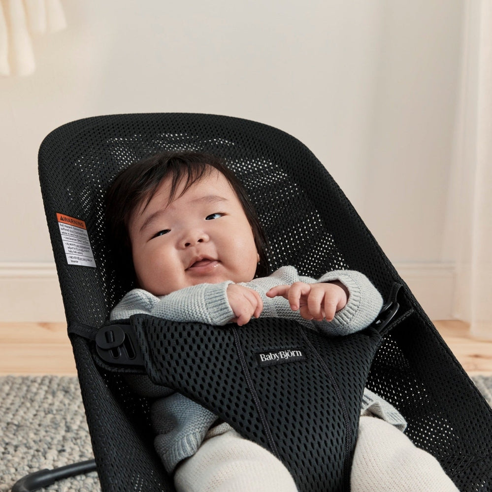 BabyBjörn Bouncer Bliss Black Mesh in use, baby smiling while supported in the mesh seat.