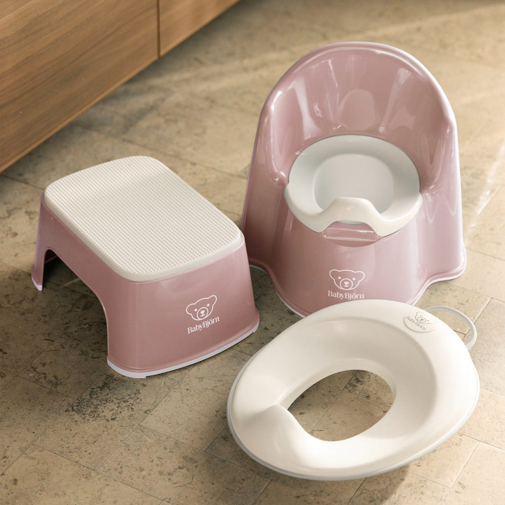 BabyBjörn Potty Chair set in pink with textured step stool and white toilet-ring seat on tiled floor.