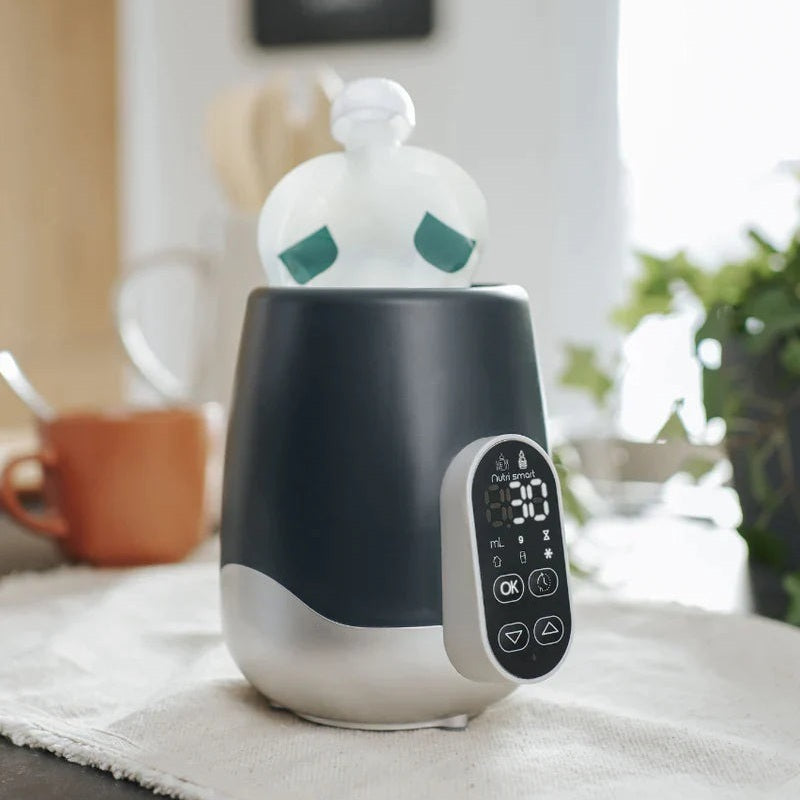 Babymoov Duo Smart bottle warmer with digital remote; dark gray body, silver base on kitchen counter