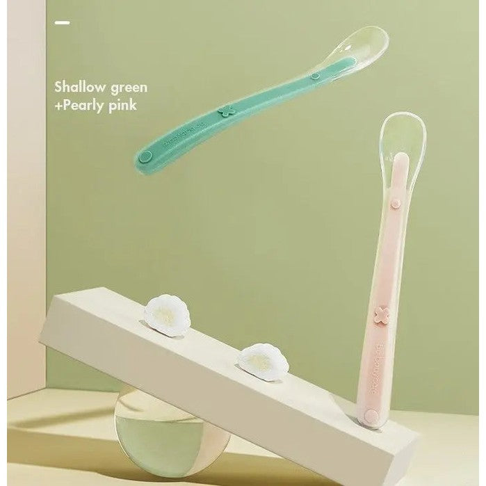 BC Babycare Baby Silicone Spoon Set in shallow green and pearly pink with looped handles shown suspended over a display.