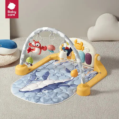 BC Babycare Bluetooth Kick & Play Piano Gym with yellow frame and hanging toys; baby kicks to activate the piano.