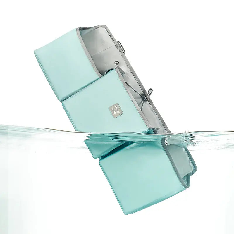 BC Babycare Hanging Storage Bag in mint teal with grey interior, shown hanging above water with its reflection.
