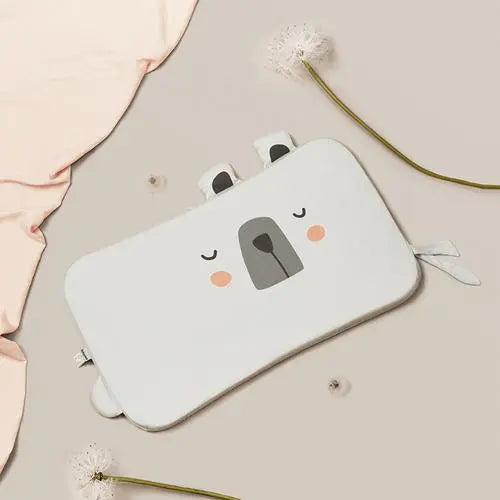 BC Babycare Latex Anti Acarien Pillow for babies, white with a cute bear-face, laid on a soft beige surface