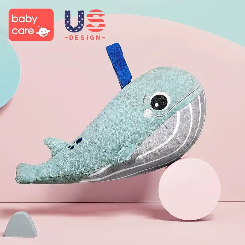 BC Babycare Light & Musical Comforter Plush whale balanced on a pink wheel in a soft pastel scene.