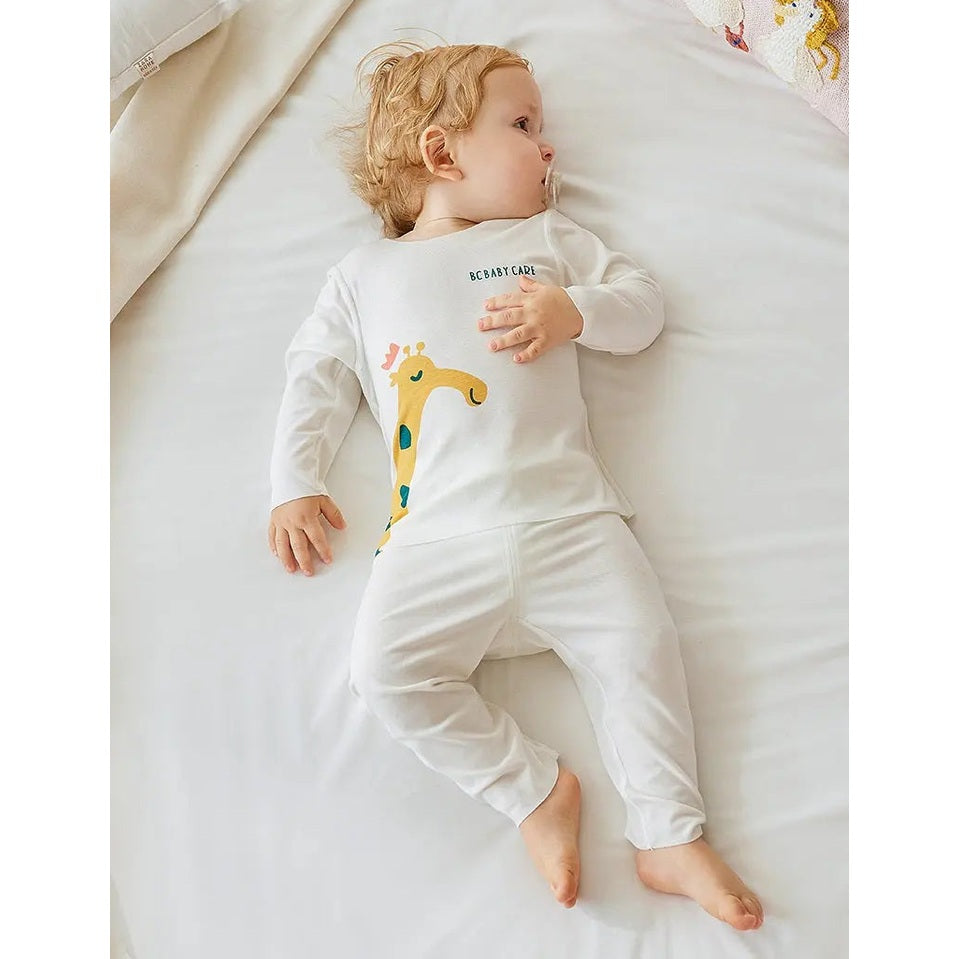 Bc Babycare Modal Sleepsuit Cream; white sleepsuit with yellow giraffe print worn by a peacefully sleeping baby.
