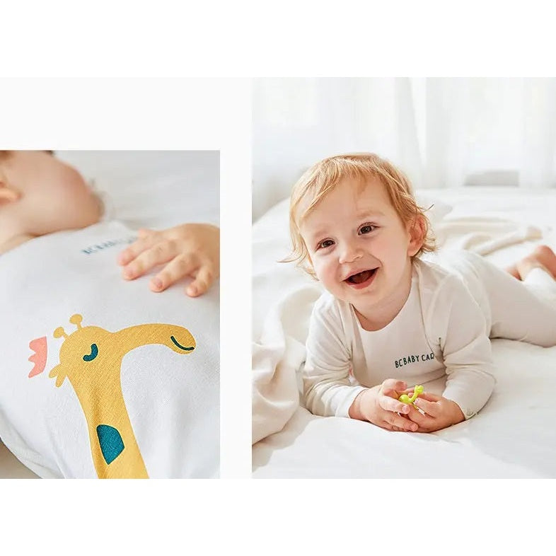 BC Babycare Modal Sleepsuit Cream, soft cream fabric with visible logo as baby smiles on a white bed.