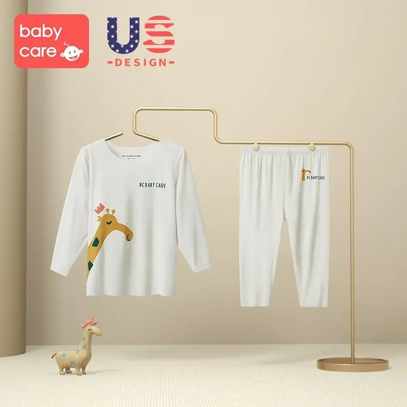 BC Babycare Modal Sleepsuit Cream: white long-sleeve top with giraffe graphic and matching pants on a display rack.