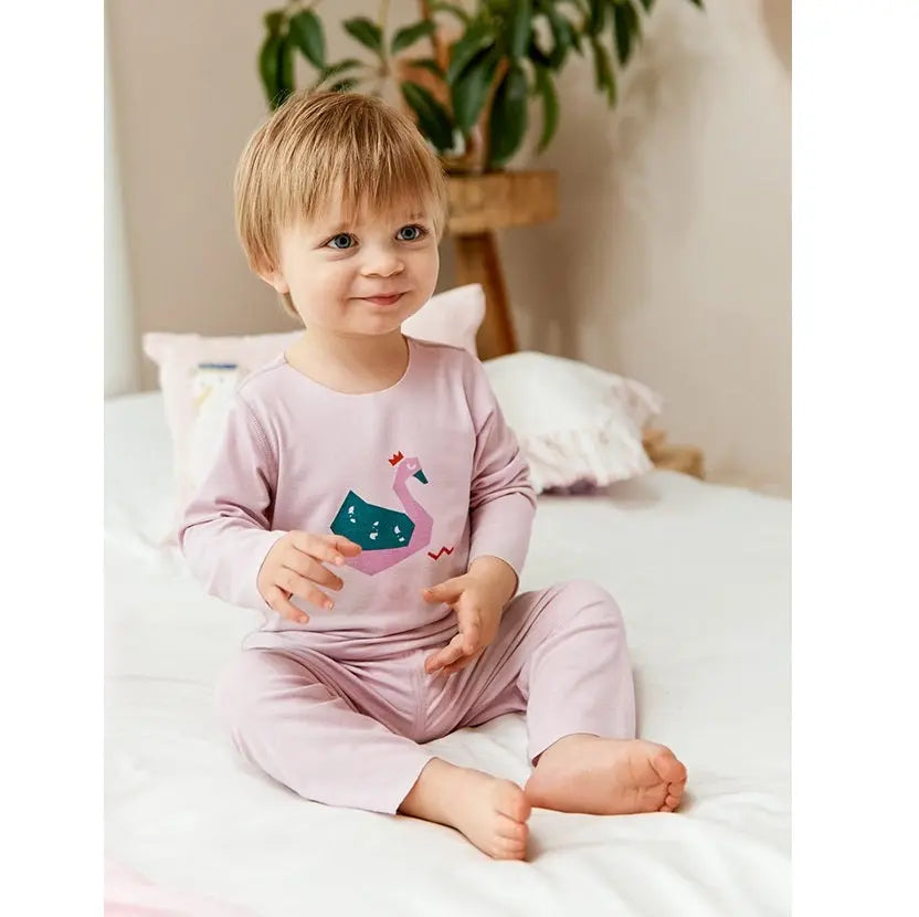BC Babycare Modal Sleepsuit Pink for toddlers, a pink sleepsuit with swan graphic worn by a smiling child on a bed.