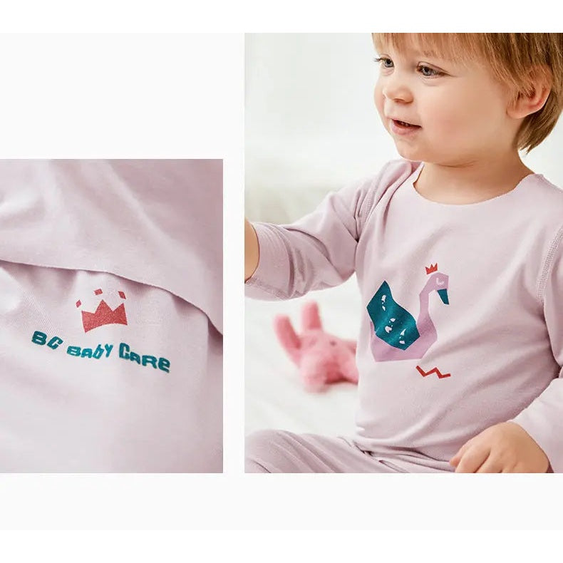 BC Babycare Modal Sleepsuit Pink; baby in pastel pink sleepwear reaching toward a plush swan toy.