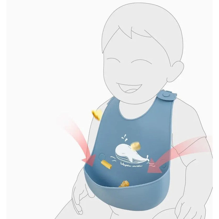BC Babycare Silicone Adjustable Bib in blue with whale graphic catching crumbs during mealtime.