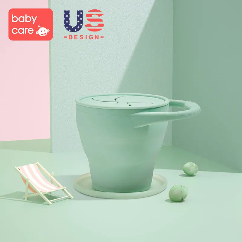 BC Babycare Silicone Collapsible Snack Cup with Lid in mint green resting on a saucer, showing portability.
