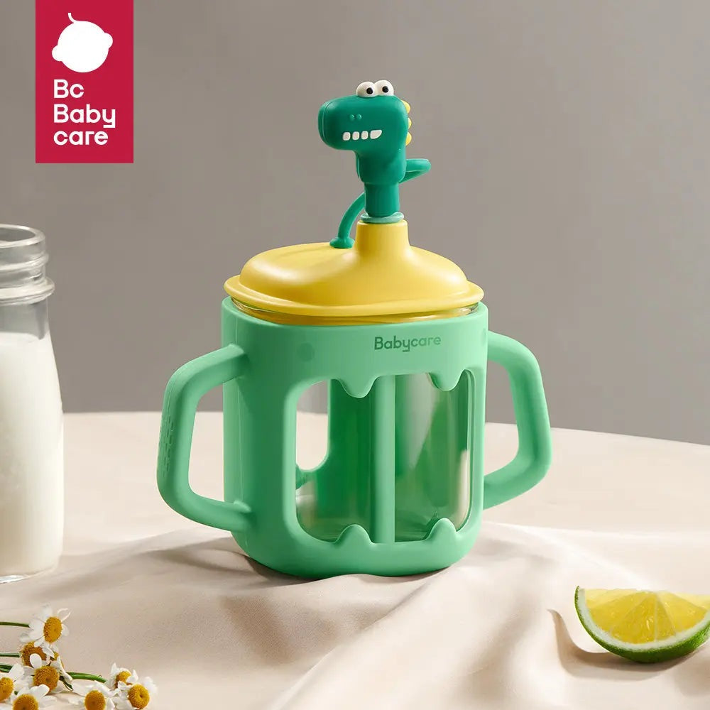 Bc Babycare T-Rex Toby Glass Sippy Cup green with yellow lid; dinosaur topper sits atop the cup with dual handles.
