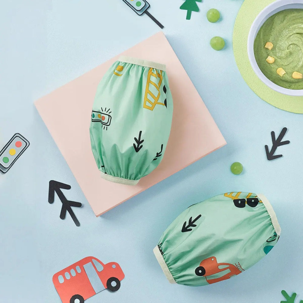 BC Babycare Waterproof Arm Sleeve set, mint green with playful prints, two sleeves laid out for mealtime and playtime.
