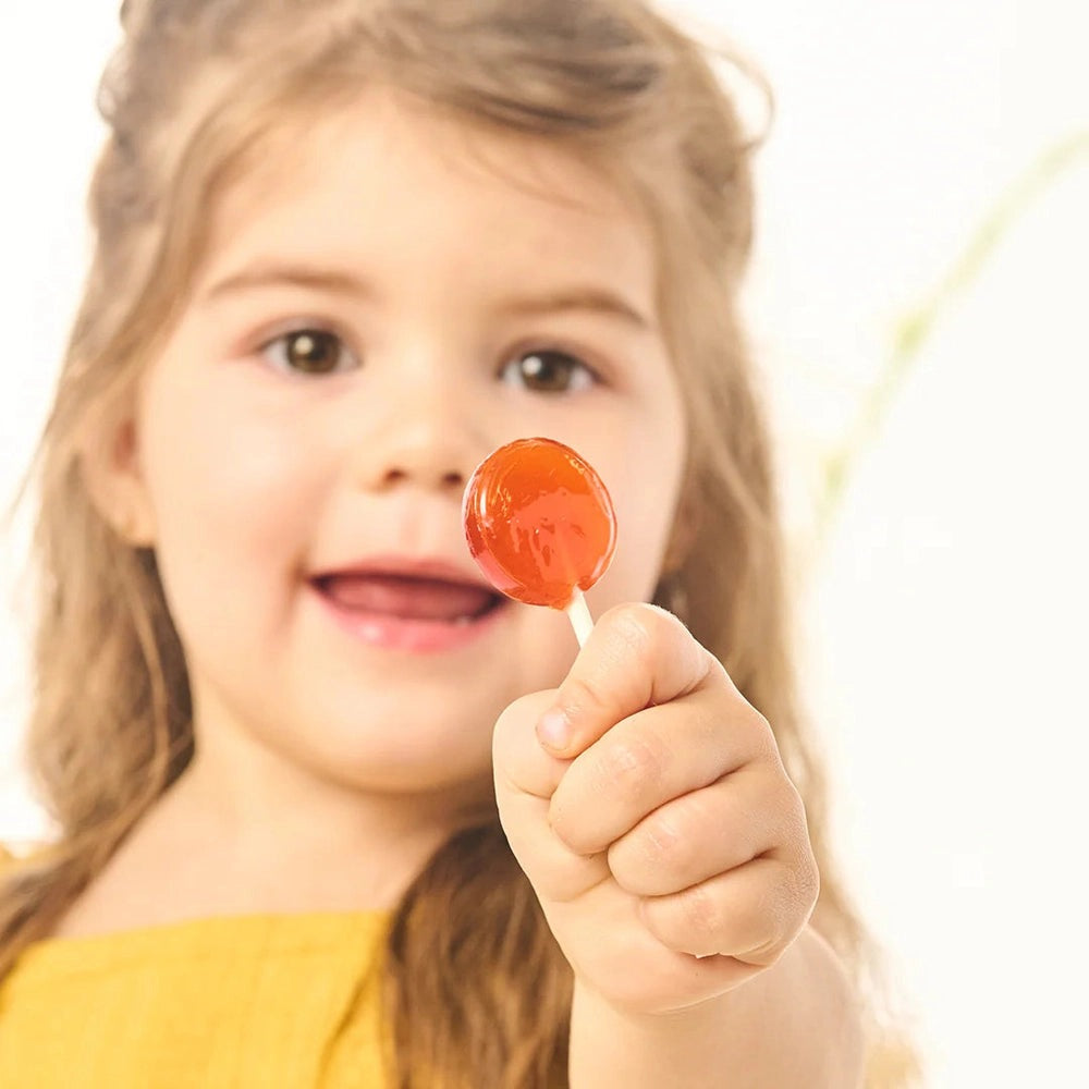 Beekeeper's Naturals Kid’s Immune Support Wellness Wands 15 ct, smiling child holds a red wellness wand.